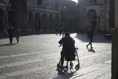 Cremona, Italy - September 22nd 2025 Elderly man with a rollator sitting in the main square of Cremona, Italy, enjoying a moment of rest in the late afternoon sun