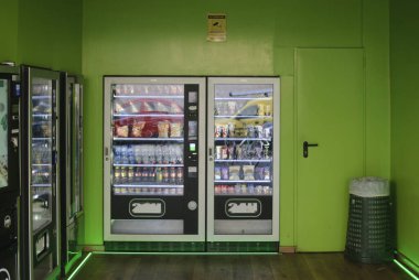 Cremona, Italy - September 30th 2025 Row of self-service vending machines offering various snacks and beverages, set in a brightly lit room with vibrant green walls