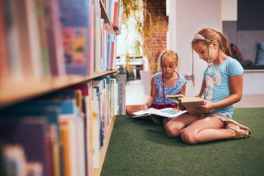 Okul kütüphanesinde okumak için kitap arayan liseli kızlar. Öğrenciler okumak için kitap seçiyorlar. Kitaplardan öğreniyorum. Okula dönelim. İlköğretim. Ödev yapıyorum.