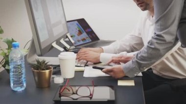 İş arkadaşları ofiste finansal verileri tartışıyor. Bilgisayarda ve akıllı telefonlarda çizelgeler ve masalarla çalışan girişimciler. Birlikte çalışan insanlar. Ofis işi