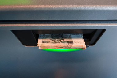 Polonya Zloty banknotlarındaki bir ATM 'den para çekmek. Banka kartı ya da telefon uygulaması kullanarak banka hesabından çek. Banka para makinesini güvene alın. Nakit para kutusundan çek. Finansal işlem konsepti. Parayı alıyorum. Polonya parası. Lehçe curr