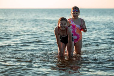 Polonya 'da Baltık Denizi kıyısında oynayan çocuklar. Yaz tatilinde suda oynayan kızlar. Deniz kenarında aile tatili. Aktif boş zaman. Neşeli yaz anları. Şişirilebilir oyuncakla oynamak