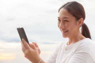 Asyalı kadınlar, sabah deniz ve sahilde cep telefonlarıyla fotoğraf ve video görüşmeleri yapıyorlar. Tatildeyken internete yüklemek için akıllı telefonlar kullanıyorlar..