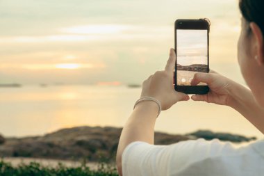 Asyalı kadınlar, sabah deniz ve sahilde cep telefonlarıyla fotoğraf ve video görüşmeleri yapıyorlar. Tatildeyken internete yüklemek için akıllı telefonlar kullanıyorlar..