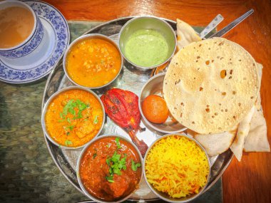 Geleneksel Hint mutfağı. Restorandaki masada çeşitli Hint yemekleri yiyorum. Hint mutfağının aperatifleri ve yemekleri. Köri, pirinç, samosa, naan, tereyağlı tavuk, chutney, baharatlar, Palak Paneer, Tikka, Roti