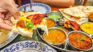 Geleneksel Hint mutfağı. Restorandaki masada çeşitli Hint yemekleri yiyorum. Hint mutfağının aperatifleri ve yemekleri. Köri, pirinç, samosa, naan, tereyağlı tavuk, chutney, baharatlar, Palak Paneer, Tikka, Roti