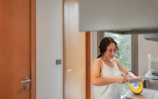 Pozitif Asyalı kadın ev hanımı mutfakta sağlıklı vejetaryen yemekleri pişiriyor. Ev işleri yapan mutlu bir kadın. Asyalı kadın mutfak masasında sebze doğradı.