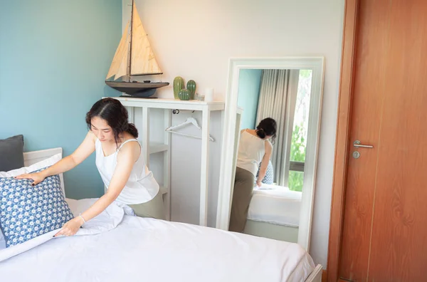 Positive Asian woman housewife tidying modern home. Happy woman doing domestic chores. Asian housewife Wiping shelf, furniture, bed, mirror, sofa, and home appliances.