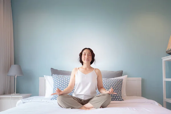 Asian woman practicing yoga lesson at home. Asian woman housewife's hobby Online training practicing yoga , breathing, meditating smiling relaxed, for Well being, wellness