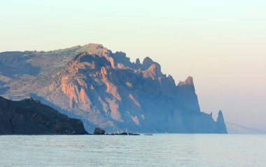 Kara-Dag dağı etkin olmayan bir volkandır. Akşam sisinde deniz yüzeyindeki kayalık dağlar. Bu bölge Kırım 'da bir doğa koruma alanıdır..