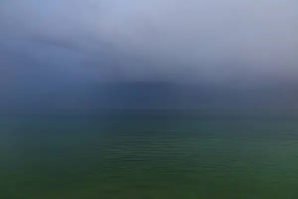 Fırtınalı havada kasvetli deniz manzarası. Yağmurlu havada deniz yüzeyinde şiddetli gök gürültülü bulutlar. Kasvetli yağmurlu havalarda ve şiddetli gök gürültülü bulutlarda denizin yüzeyinde.