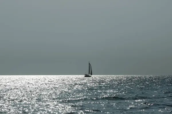 Yalnız bir yelkenli. Deniz manzaralı, yelkenli geminin silüeti dramatik bir ışık altında..