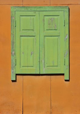 Eski mühürlü ahşap pencere. Turuncu duvardaki ahşap yeşil pencere kapalı..