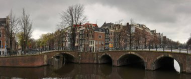 Amsterdam, Hollanda - 9 Nisan 2012: Bulutlu bir günde Amsterdam 'ın köprüleri ve evleri. Şehrin tarihi bölgesinde Keizersgracht ve Reguliersgracht caddelerini geçerek.