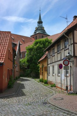 Luneburg 'da klasik cadde, Aşağı Saksonya, Almanya. Eski geleneksel mimari ve Luneburg 'daki St. Michaelis kilisesinin kulesi..
