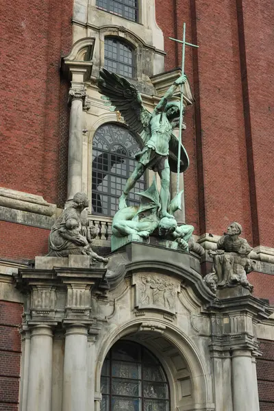 Dini heykel kompozisyonu. Başmelek Michael 'ın bronz heykeli Hamburg' daki St. Michael Kilisesi 'nin ana kapısının üzerinde yer almaktadır..