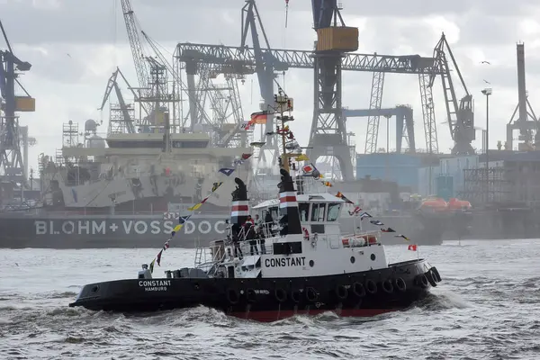 Hamburg, Almanya - 12 Mayıs 2012: Bir römorkör Hamburg limanında bir tersane vincinin siluetine karşı manevra yapıyor.