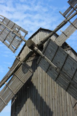 Tahta yel değirmeni. Mavi gökyüzüne karşı gıcırdayan eski yel değirmeninin mahvolmuş bıçakları yakın plandaydı. Yel değirmeni Ukrayna 'daki Dinyeper nehrinin kıyısında yer almaktadır..