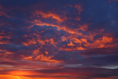 Fırtınalı bulutlarla gün batımı gökyüzü arkaplan ya da doku olarak ateşli tonlarda.