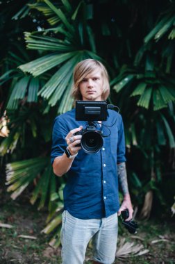 Kameraman dışarıda kamerasıyla ve vibratörüyle dikiliyor. Seçici odak