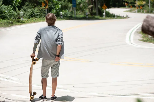 一个在路上有滑板的年轻人 高质量的照片 — 图库照片