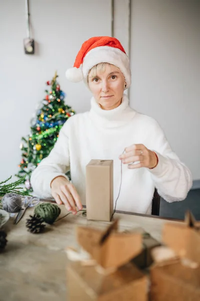 圣诞礼帽女人们在家里用环保材料包装圣诞礼物 — 图库照片