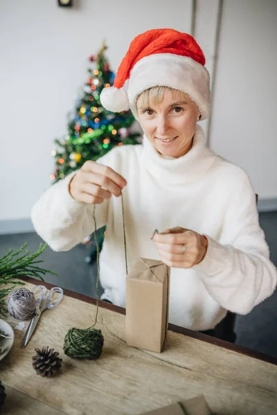 Kobieta Kapeluszu Mikołaja Pakowanie Prezentów Świątecznych Materiałów Ekologicznych Domu — Zdjęcie stockowe