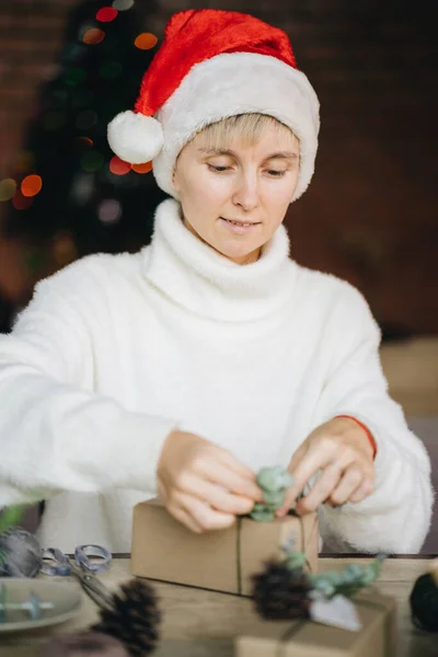 Perempuan Santa Hat Wrapping Natal Menyajikan Dengan Bahan Eko Rumah — Stok Foto