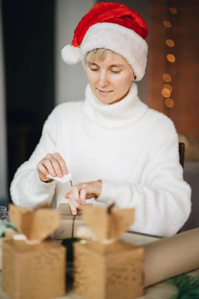 Perempuan Santa Hat Wrapping Natal Menyajikan Dengan Bahan Eko Rumah — Stok Foto
