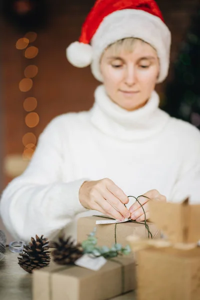 Kobieta Kapeluszu Mikołaja Pakowanie Prezentów Świątecznych Materiałów Ekologicznych Domu — Zdjęcie stockowe