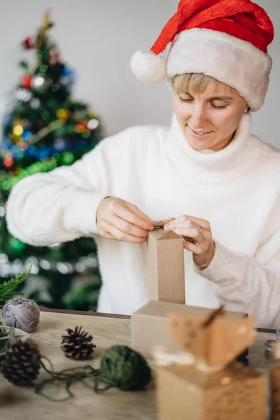 Perempuan Santa Hat Wrapping Natal Menyajikan Dengan Bahan Eko Rumah — Stok Foto