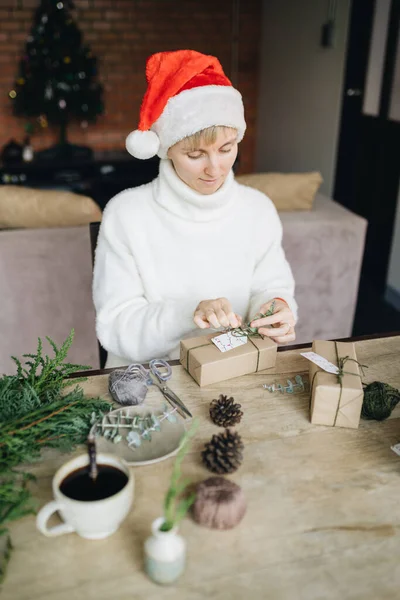 圣诞礼帽女人们在家里用环保材料包装圣诞礼物 图库图片
