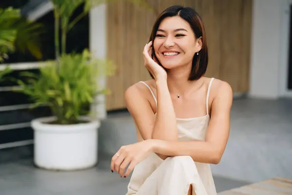 Aantrekkelijke Aziatische Vrouw Een Beige Jurk Zit Buiten Hoge Kwaliteit Stockafbeelding