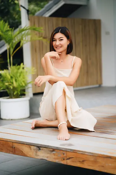 Attrayant Asiatique Femme Dans Une Robe Beige Est Assis Extérieur Photos De Stock Libres De Droits