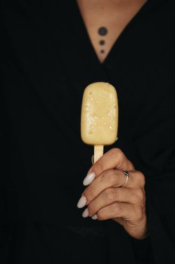 female hand is holding an ice cream eskimo at dark background. High quality photo clipart