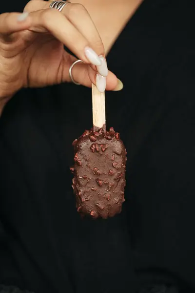 Stock image female hand is holding an ice cream eskimo at dark background. High quality photo