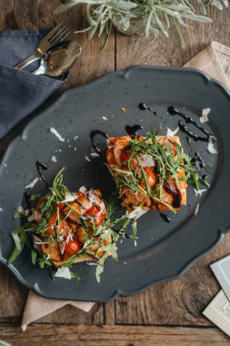 Yüksek açılı sosisli sandviç, taze domates ve ahşap bir masada roka.