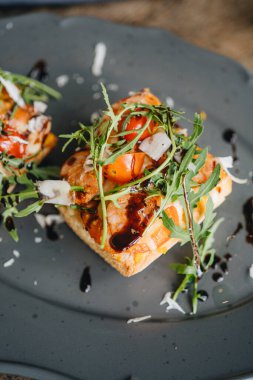 Yüksek açılı sosisli sandviç, taze domates ve ahşap bir masada roka.