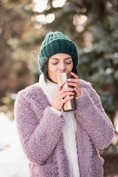 Close up portrait of woman walking on winter day, holding travel stainless Steel mug with hot coffee. reusable water bottle. Refuse, reduce, recycle and zero waste concept. Ecology