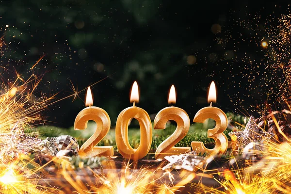 Holiday background Happy New Year 2023. Numbers of year 2023 made by gold burning candles on bokeh festive sparkling background. celebrating New Year holiday, close-up. Space for text