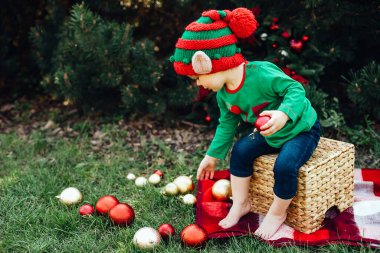 Temmuz 'da Noel. Çocuklar elf kulakları. Çocuk temmuzda Noel 'i ağaçta bekliyor. Noel ağacı süsleyen küçük bir kızın portresi. Kış tatili ve insanların konsepti. İyi tatiller..