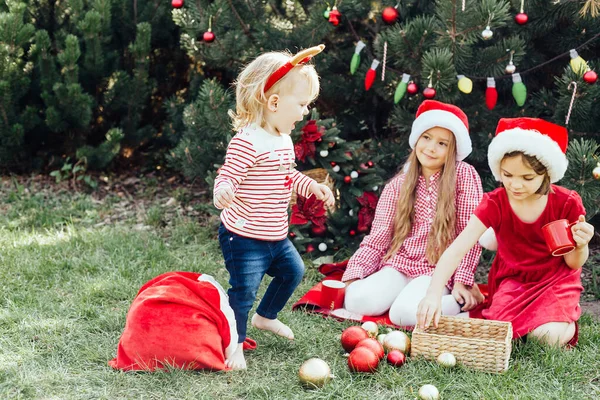 メリークリスマス サンタの帽子の3人の面白い子供たちの肖像は 楽しさを持って外でホットチョコレートを飲むジンジャーブレッドクッキーを食べています ハッピー ホリデー 休日を楽しむ子供たち 7月のクリスマス — ストック写真