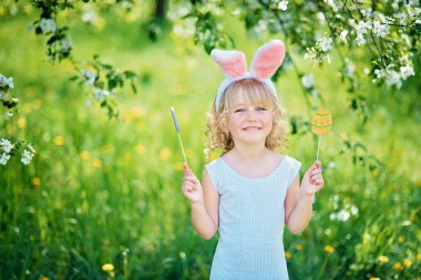 Paskalya yumurtaları ve tavşan kulakları Garden ile şirin komik kız. Paskalya kavramı. Paskalya yumurtası avı gülen çocuk. Çocuk Parkı yumurta, bahar kavramı ile