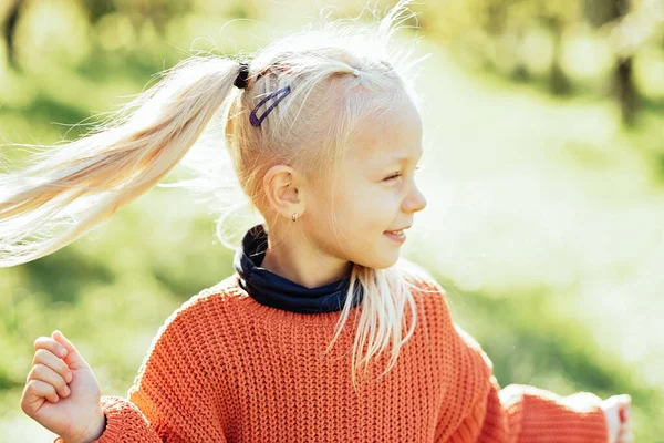 Portrait of sweet little blonde girl playing in sun outdoors. Happy little child having fun at park. Laughing child. Expressive facial with cute expression.