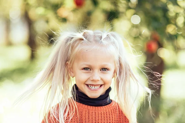 Portrait of sweet little blonde girl playing in sun outdoors. Happy little child having fun at park. Laughing child. Expressive facial with cute expression.