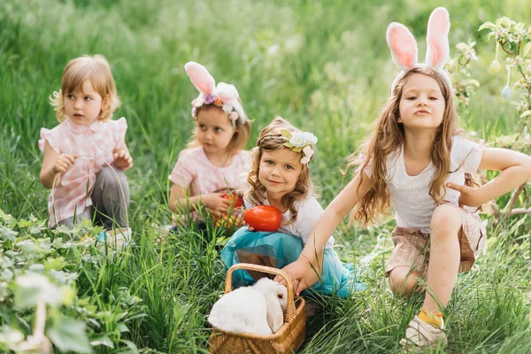 Easter egg hunt. Group Of Children Wearing Bunny Ears Running To Pick Up colorful Egg On Easter Egg Hunt In Garden. Easter tradition. Laughing children in park with basket spring concept