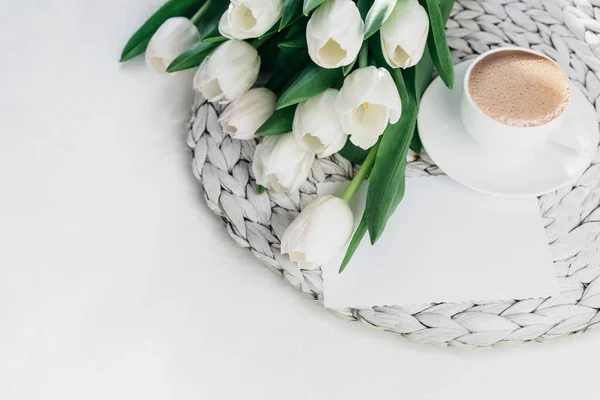 Cozy morning coffee cup with white tulip flowers from above, breakfast on Mothers day or Womens day. Top view with copy space Floral composition Romantic background