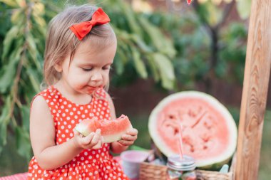 Şirin çocuk yazın sulu karpuz yiyor. Çocuk, bebek, çocuklar için sağlıklı yiyecek. Limonata satmaya çalışan sevimli küçük kız. Buzlu ve naneli karpuz limonatası.