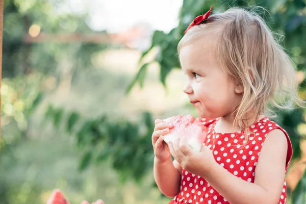 stock image Cute child eats ripe juicy watermelon at summertime. Child, baby, healthy food snack for children. Adorable little girl trying to sell lemonade. Watermelon lemonade with ice and mint