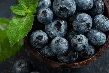 Hindistan cevizi kabında koyu arkaplanda taze toplanmış yabanmersini. Sağlıklı organik mevsimlik meyve arka planı. Meyveler yakın plan.